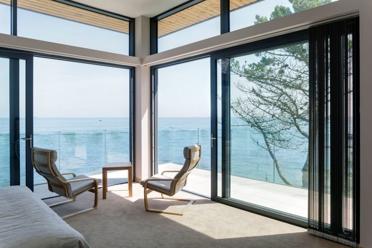Frameless glass balustrade on a sea-facing terrace behind sliding aluminum doors