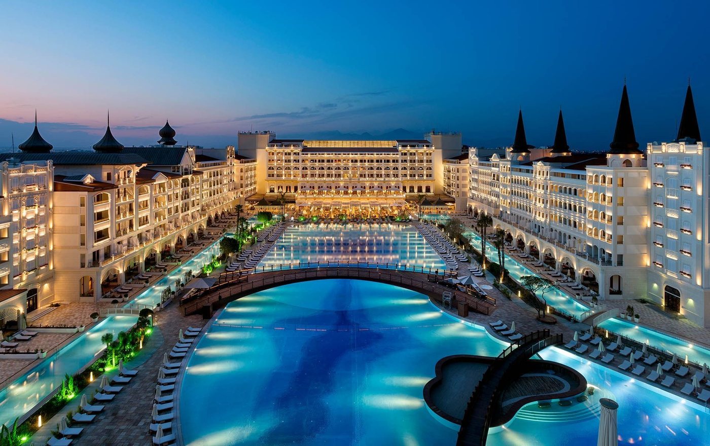 Mardan Palace Antalya illuminated at blue hour around its lagoon pool